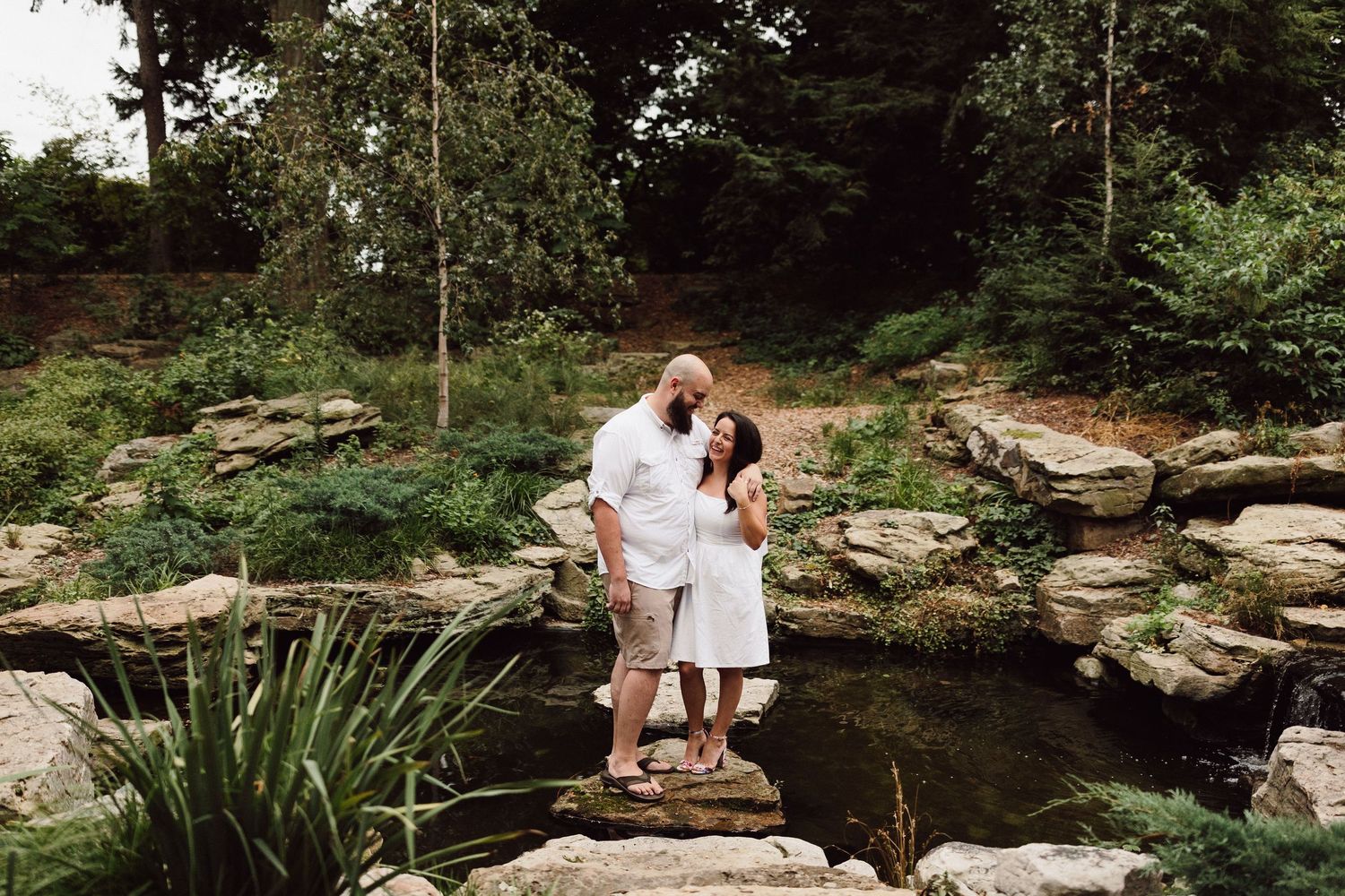 Romantic outdoor photoshoot by a scenic creek with stone landscaping.
