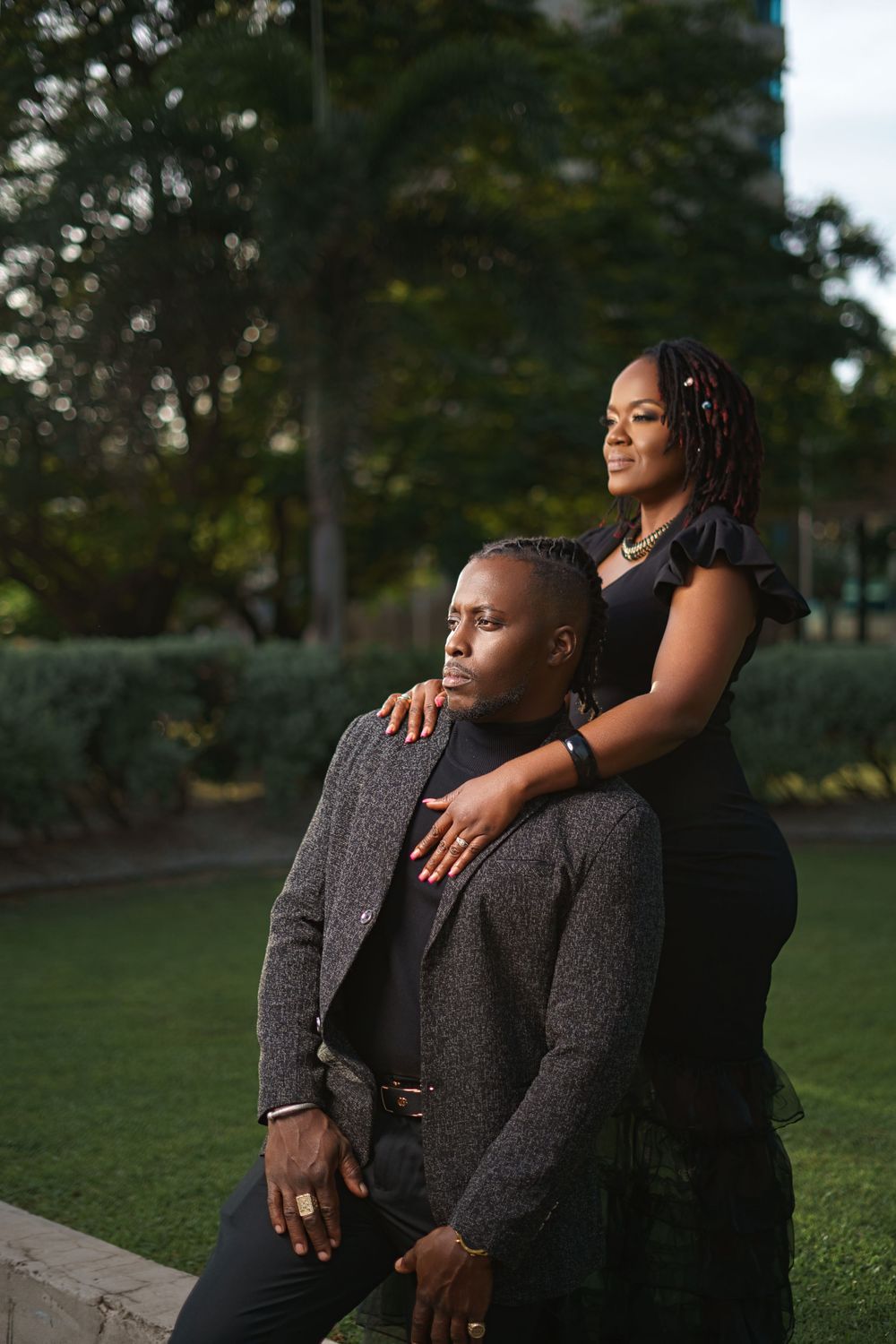 A romantic couple poses together in an outdoor garden setting during golden hour.