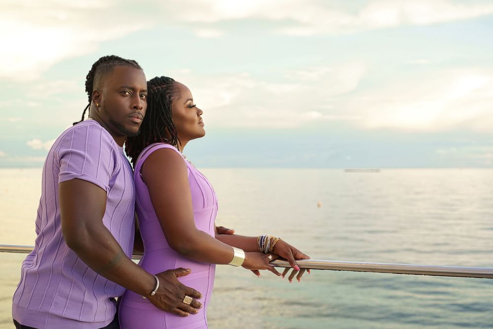 A couple in matching purple outfits shares romantic moments on a beach at sunset.