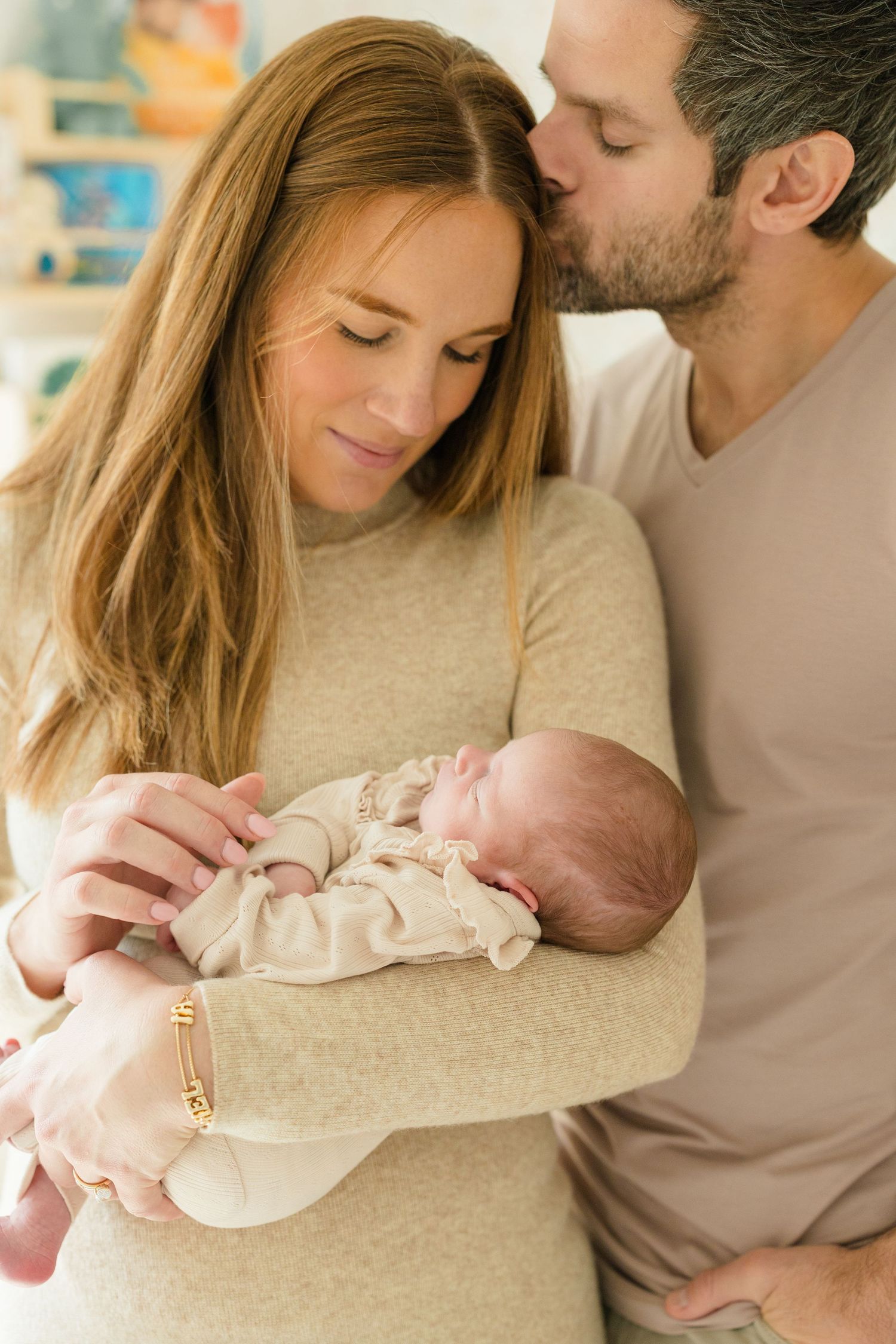 Parents lovingly embrace their newborn baby in a series of tender moments captured in soft, neutral tones.