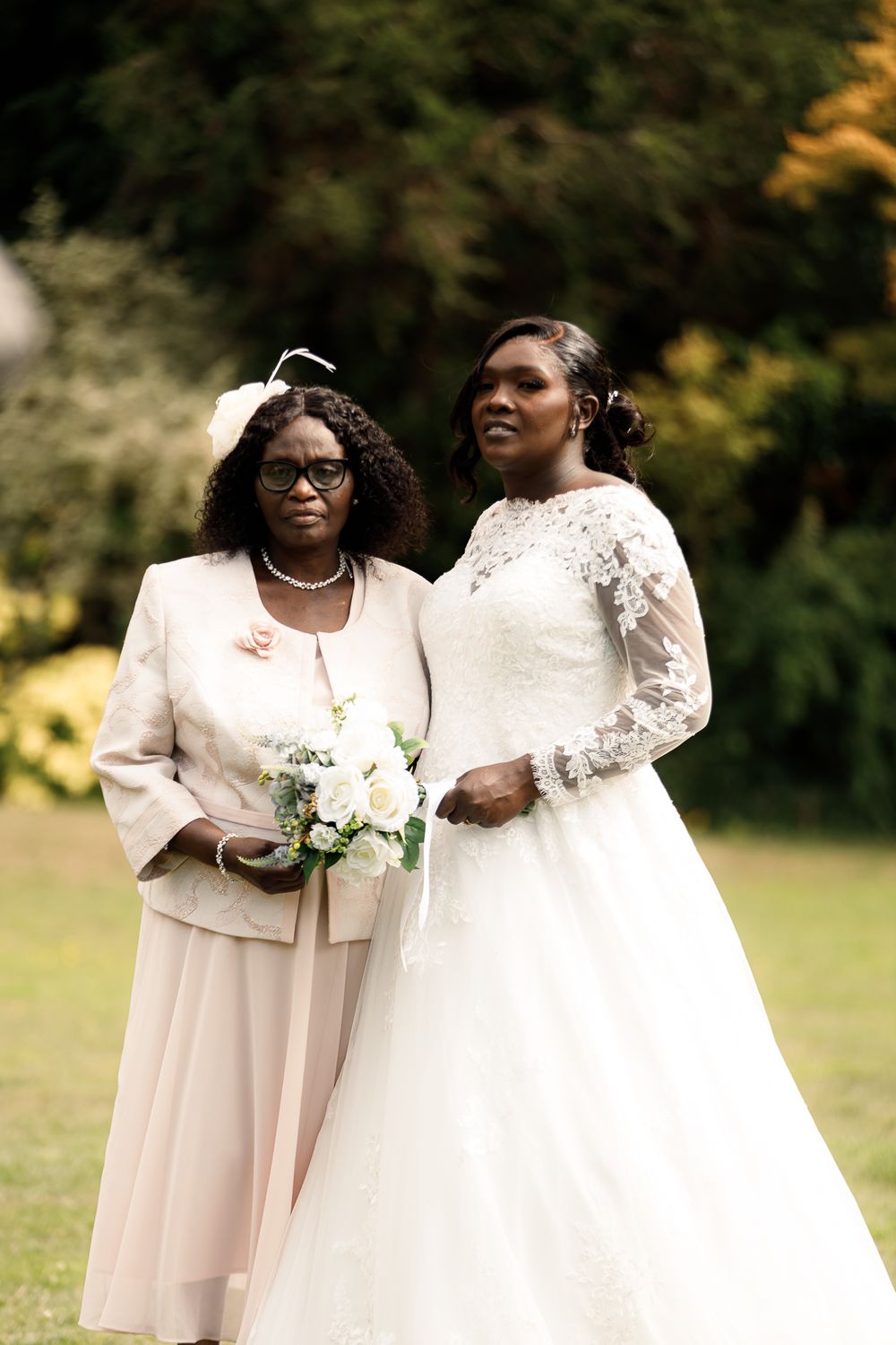 Bridesmaids in soft pink dresses share joyful moments with a bride in a white gown during outdoor wedding photos.