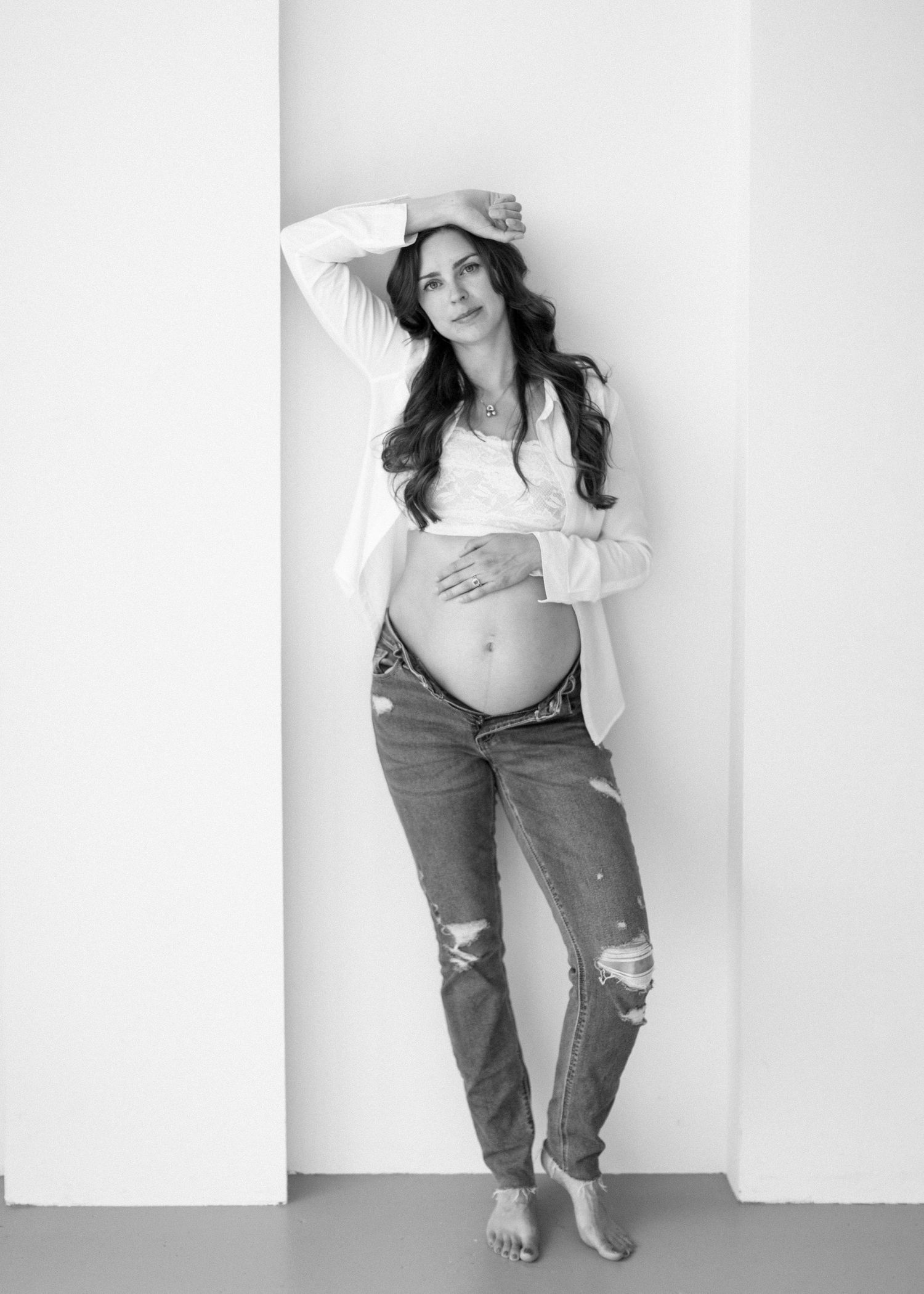 A series of black and white fashion portraits showing a person in ripped jeans and casual wear posing against a white wall.