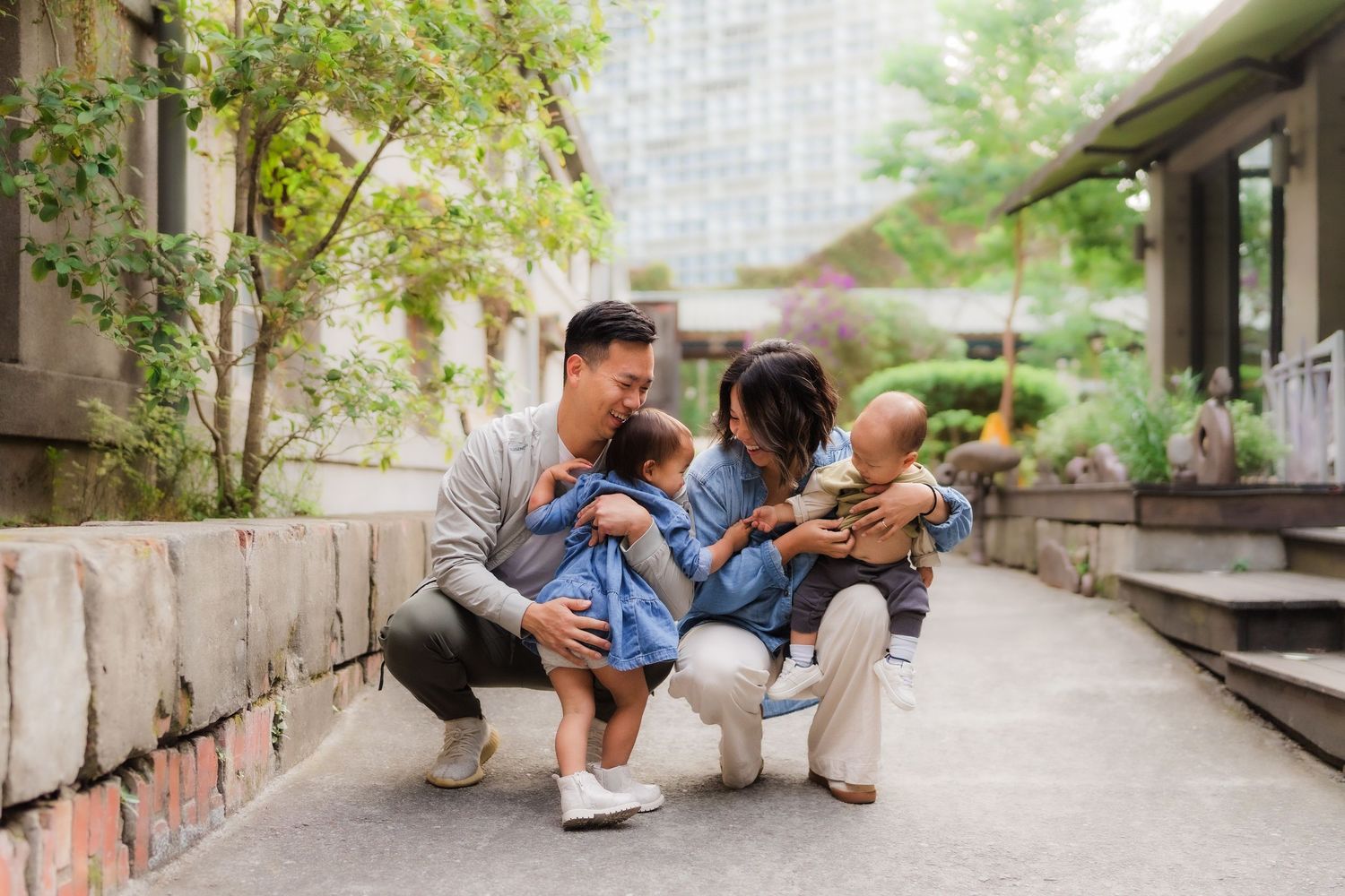 Children sit together on a concrete step in a garden setting, engaging in playful interaction.