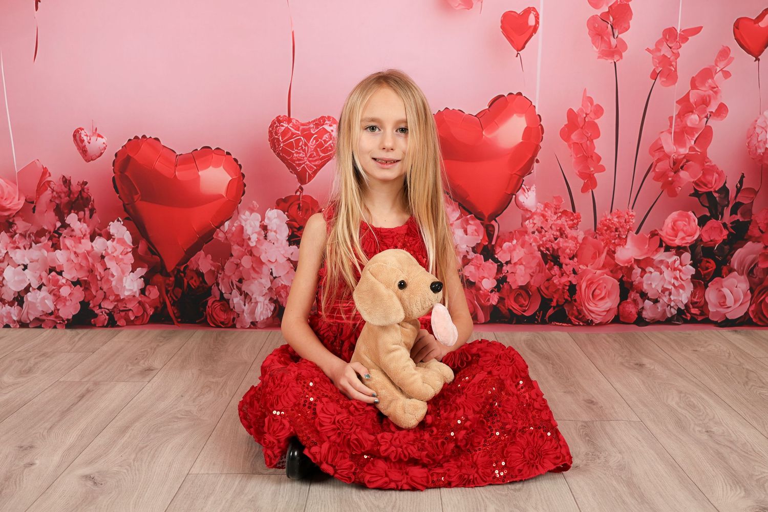 Valentine's themed photo with teddy bear and red sparkly dress surrounded by heart balloons.