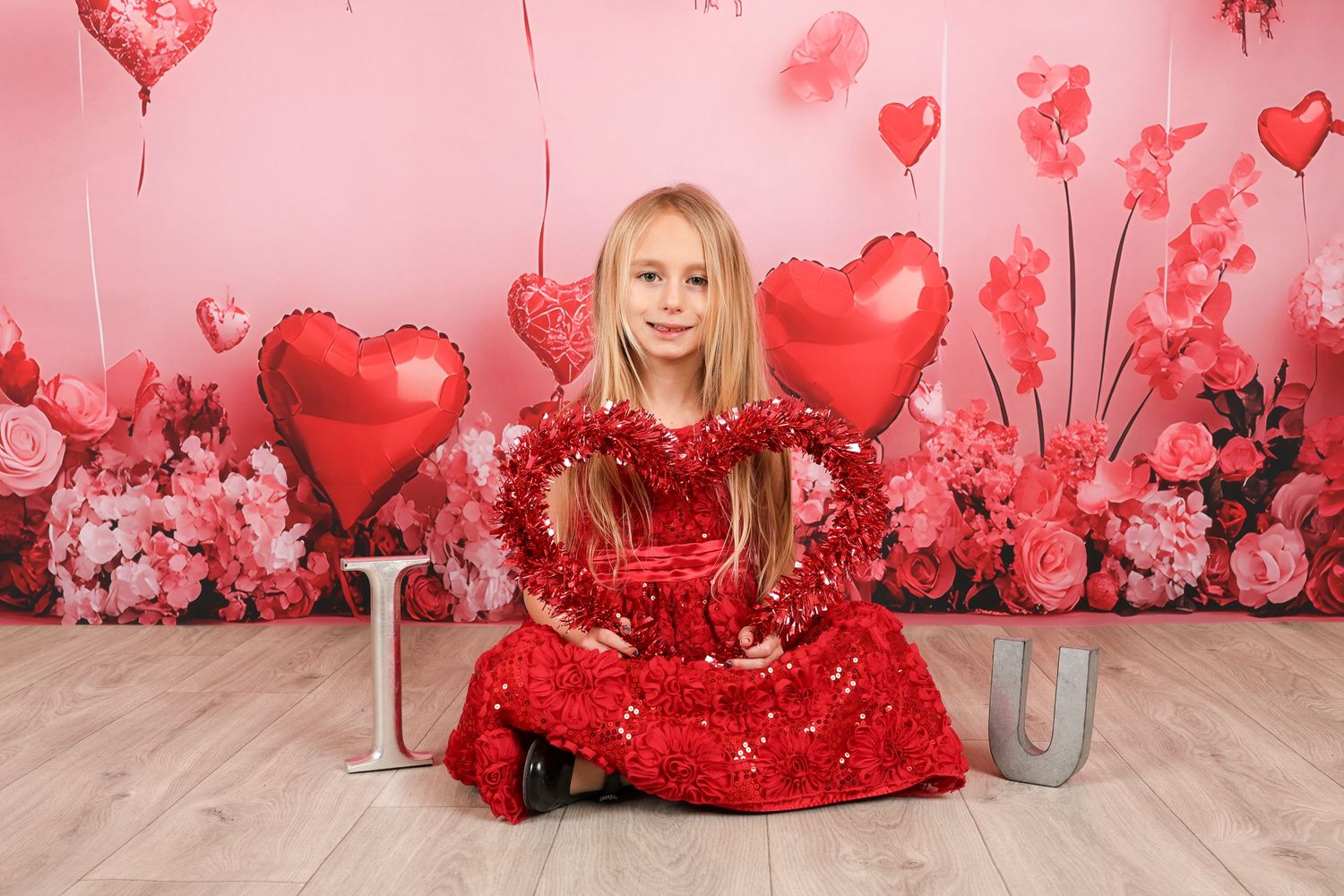 Valentine's photo setup with sparkly red dress and heart decorations on pink background.