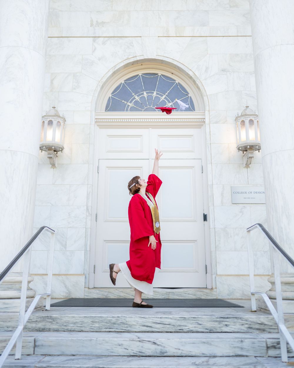 A figure in a bright red Santa suit stands in front of a white church entrance with arched doorways.