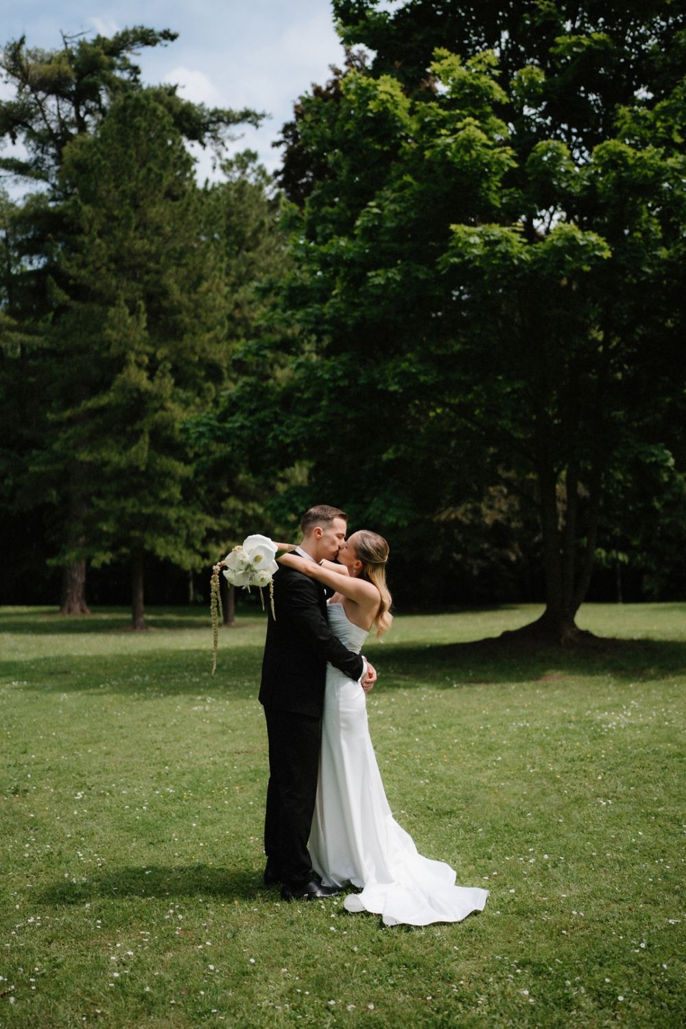 A couple shares an intimate moment during their wedding photoshoot in a sunny park.