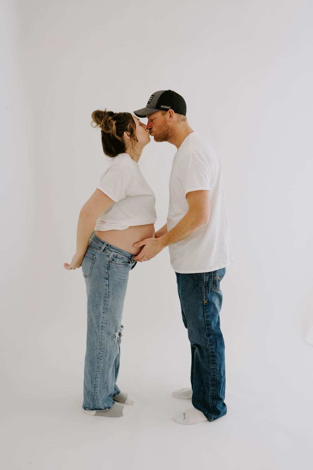 Intimate maternity photo of couple in casual wear sharing a tender moment.