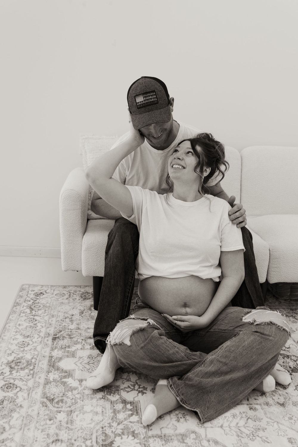 Candid maternity portrait of couple sharing intimate moment on floor.
