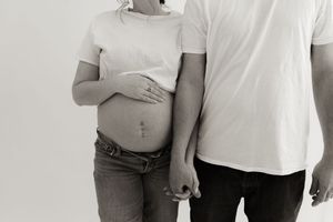 Black and white intimate portrait of expecting couple with focus on pregnant belly.