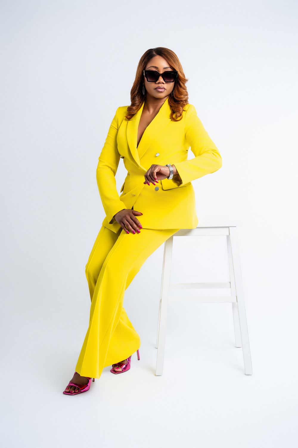 Stylish businesswoman in a yellow suit sitting on a stool for modern branding photography