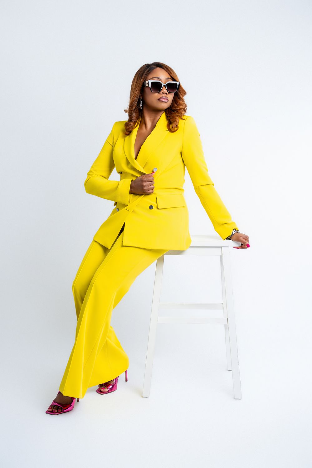 Professional woman in a yellow suit sitting confidently on a stool during a personal branding photography session