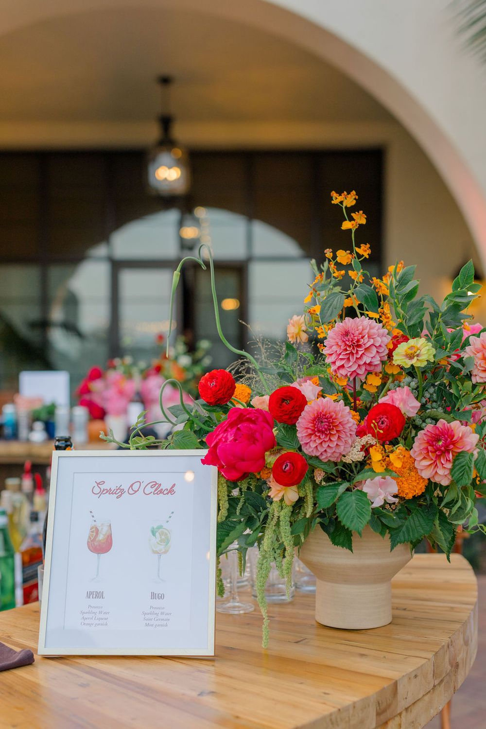 Bar menu display with colorful floral arrangement featuring dahlias and roses on wooden surface.