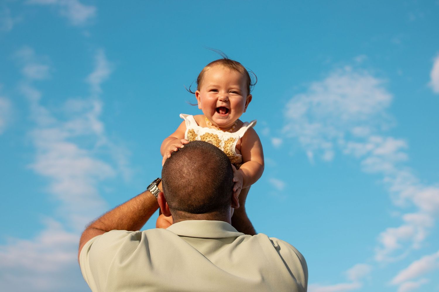 happy baby in dads arms at beach photoshoot