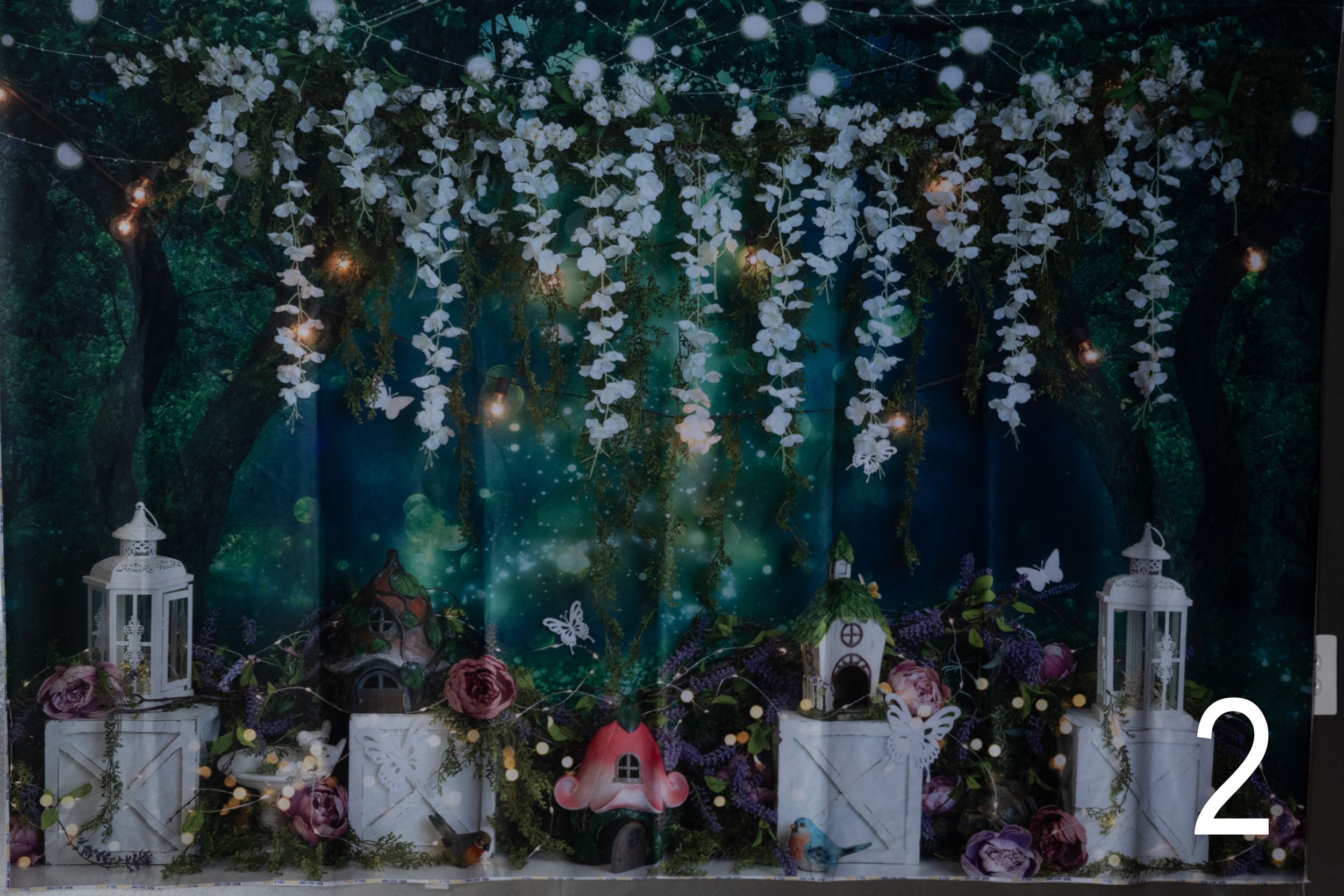 Enchanting outdoor wedding setup with hanging wisteria flowers and white lanterns creating a magical forest atmosphere.