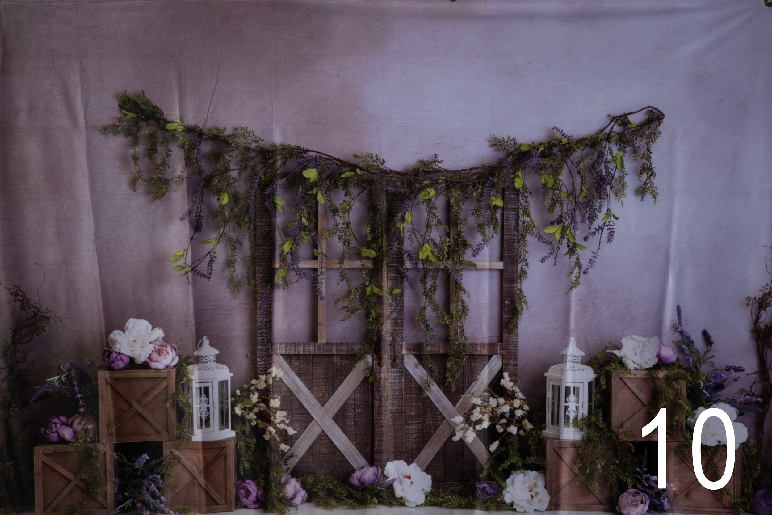 A rustic wedding venue decorated with hanging greenery, white drapes, and wooden cross beams creates an elegant atmosphere.