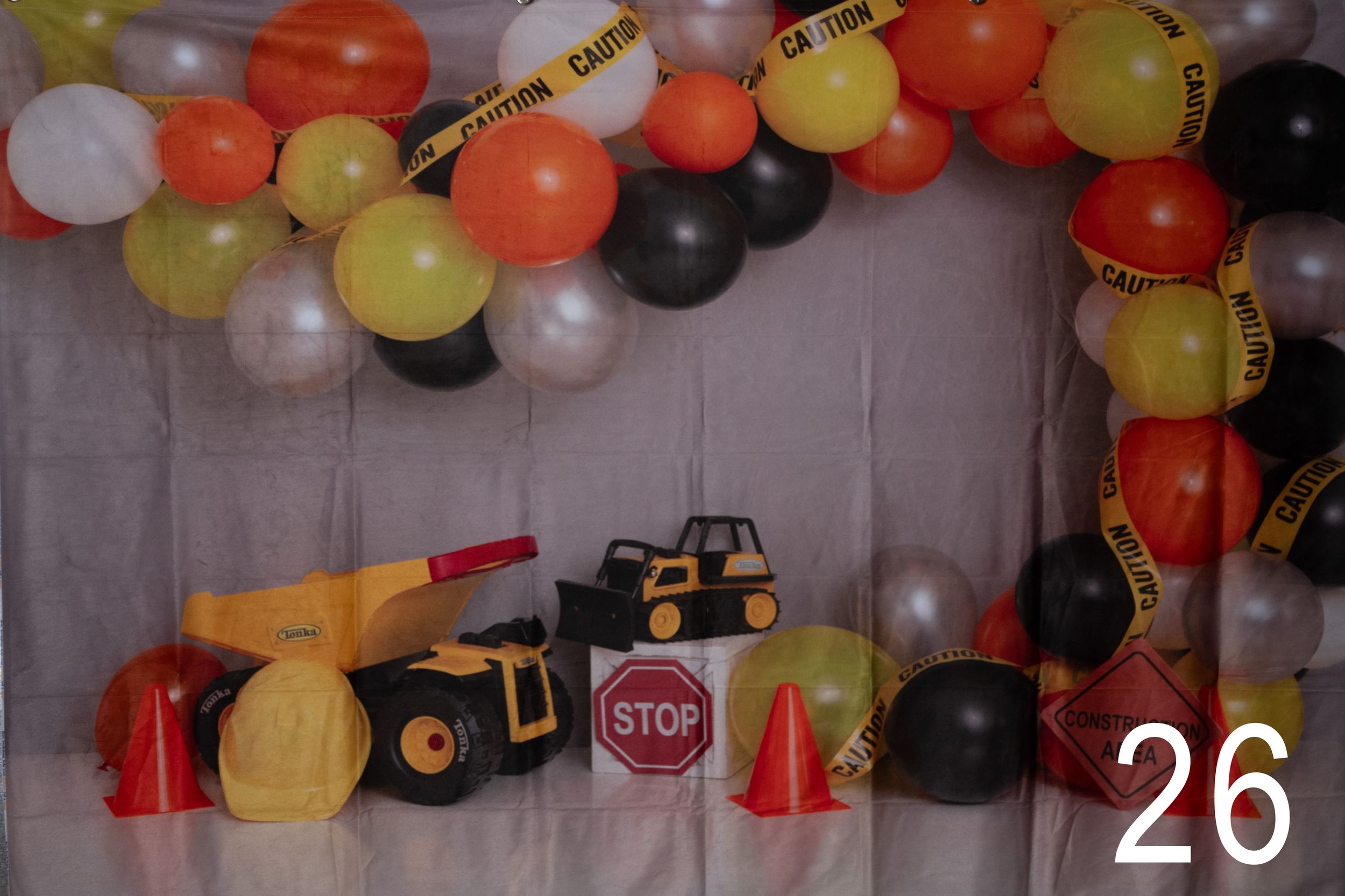 Colorful balloon arch with black, orange, yellow and white balloons decorating a party space with stop sign decor.