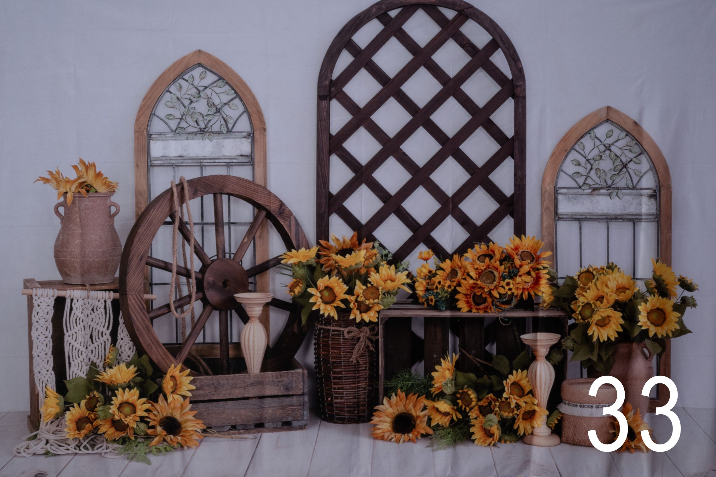 Rustic fall decor display with wooden wagon wheel, lattice panel, arched windows and sunflower arrangements.