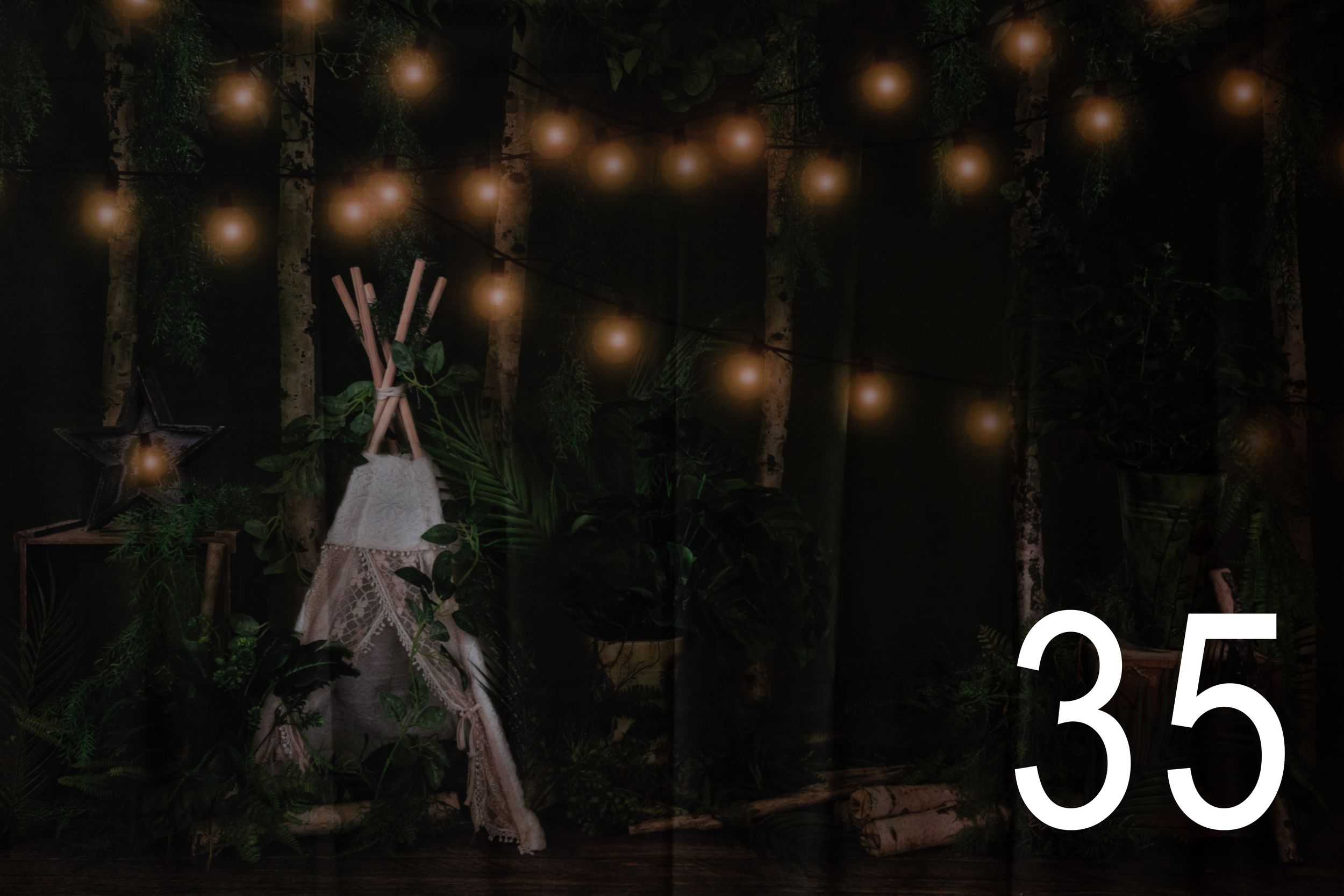 A teepee tent illuminated by string lights creates a magical woodland scene at night.