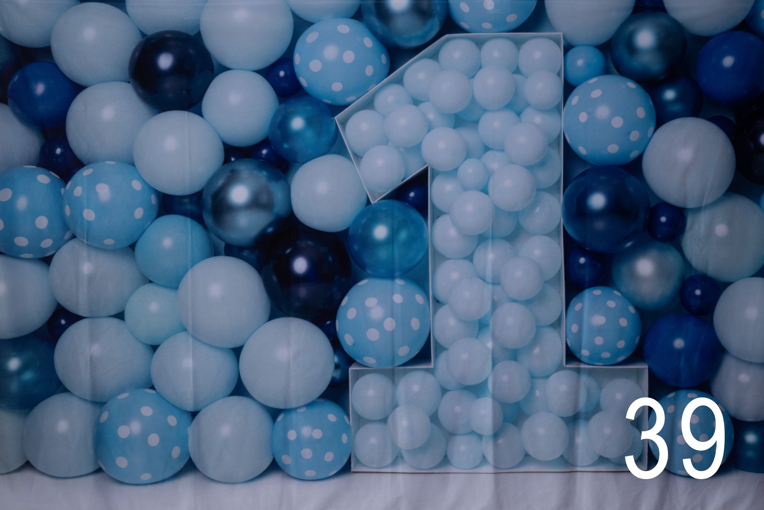 Light blue and white polka dot balloons create a festive party backdrop decoration against a dark background.