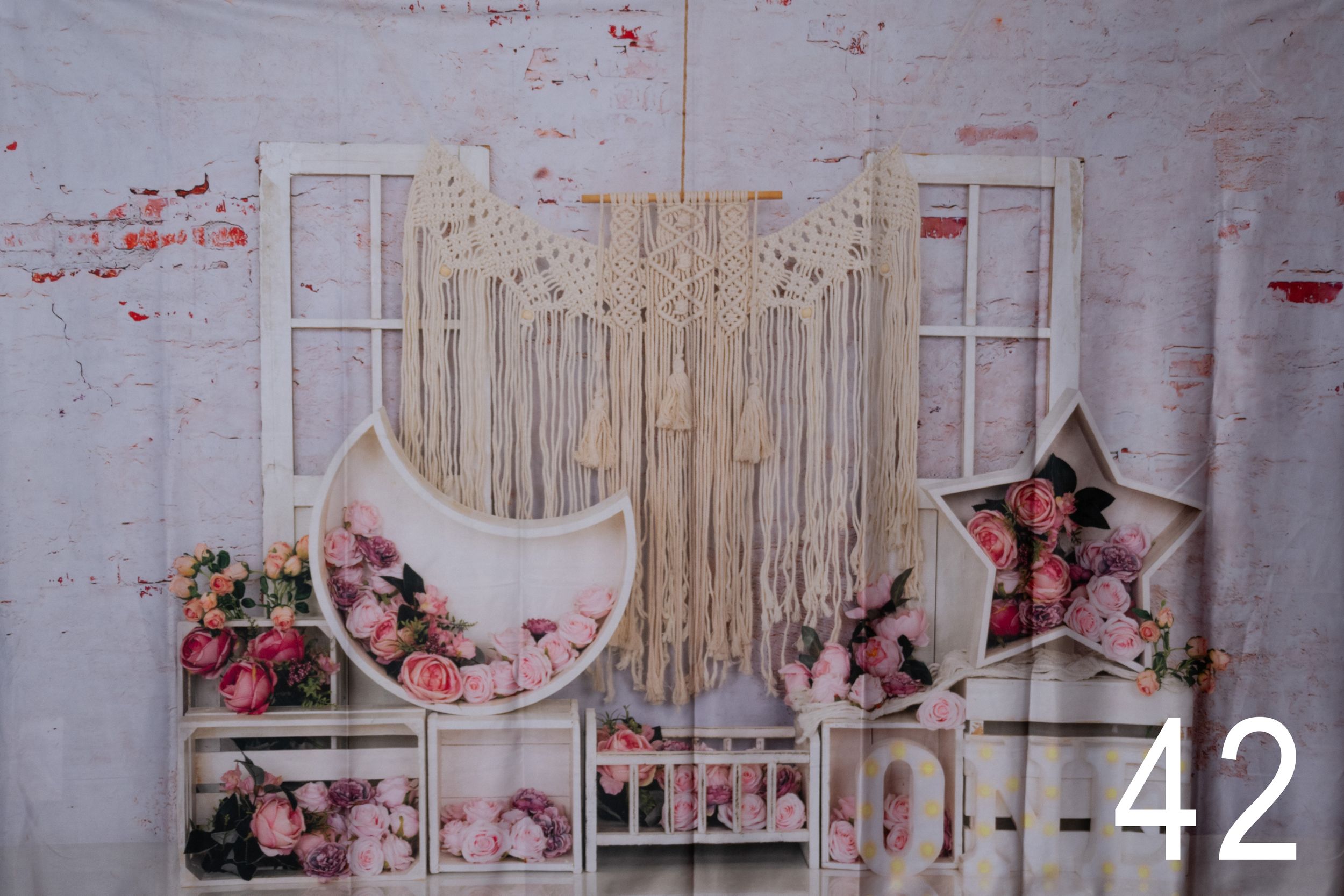 Rustic photography backdrop with macrame wall hanging, vintage windows, crescent moon and star shapes with floral accents.
