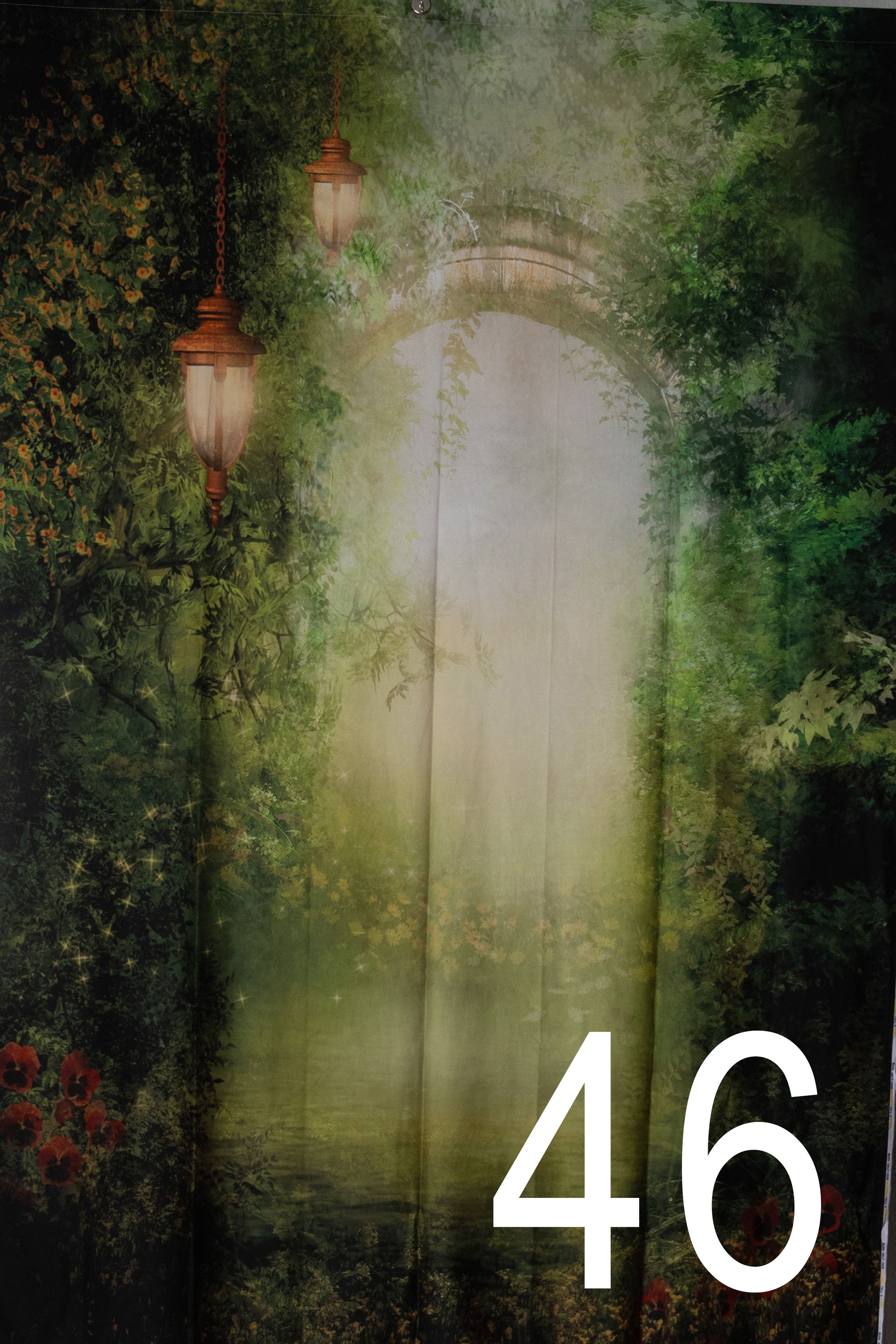 A mystical forest scene with hanging lanterns and arched doorways creates an enchanted garden atmosphere in soft green tones.