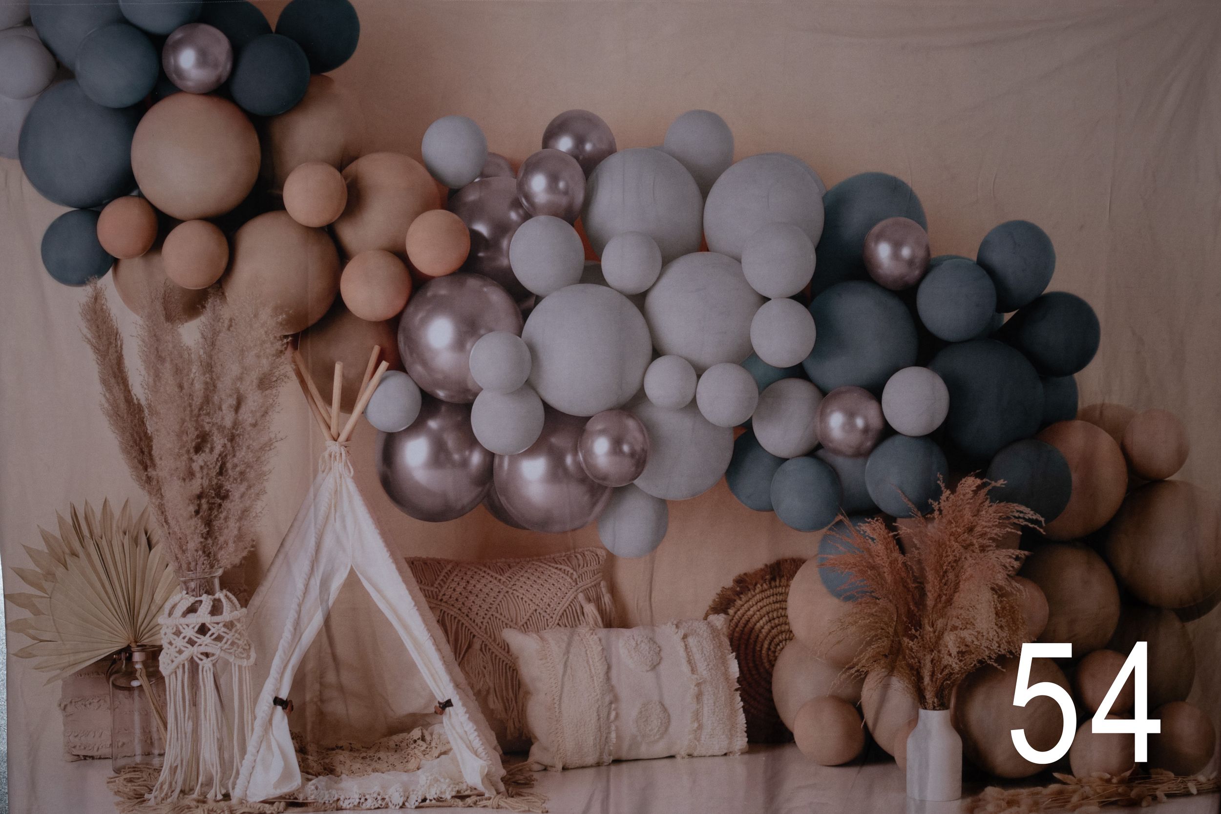 Modern party decoration featuring an arch of matte balloons in neutral gray and beige tones against a light backdrop.