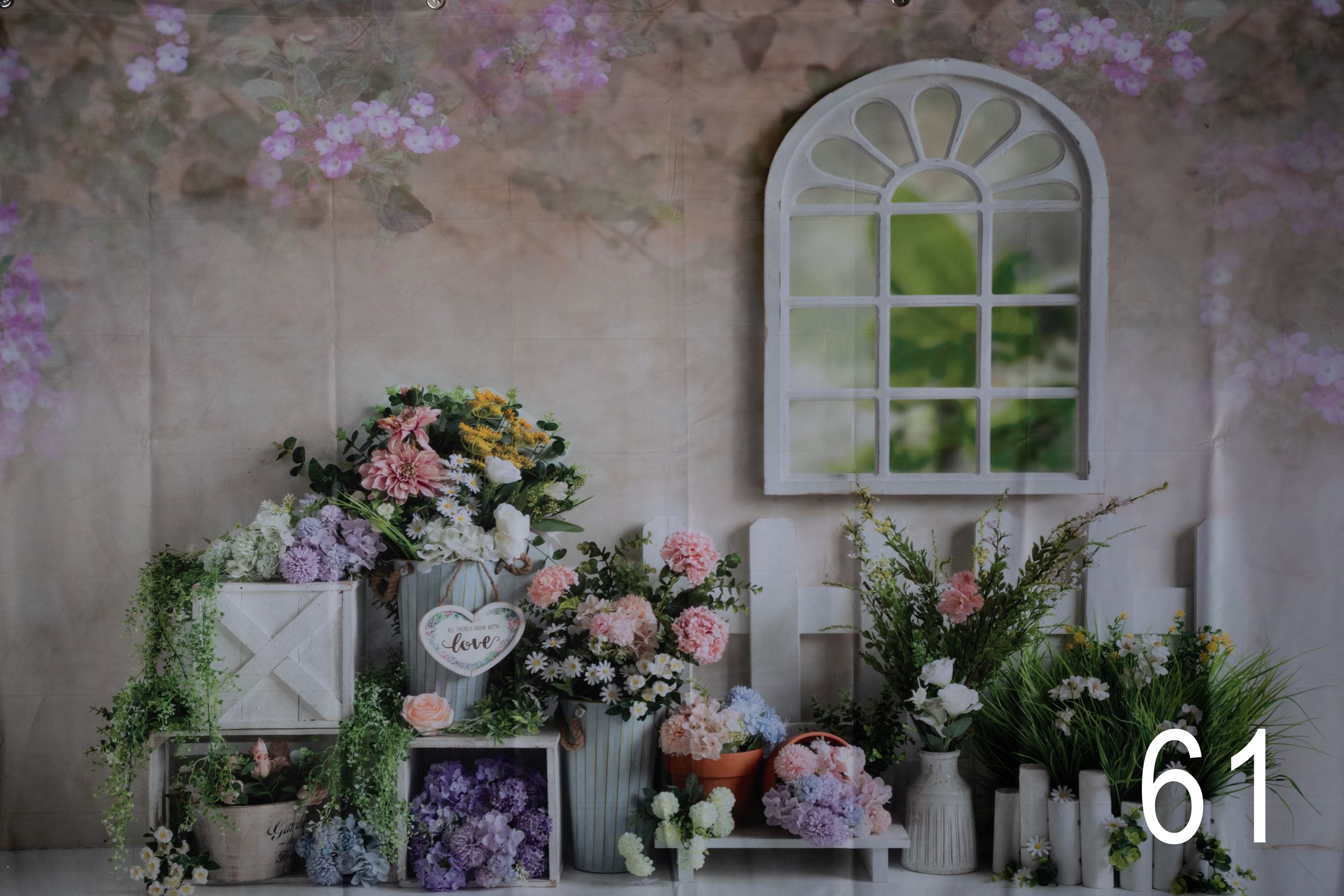 Rustic stone wall with climbing pink roses and arched windows creates a romantic garden setting.