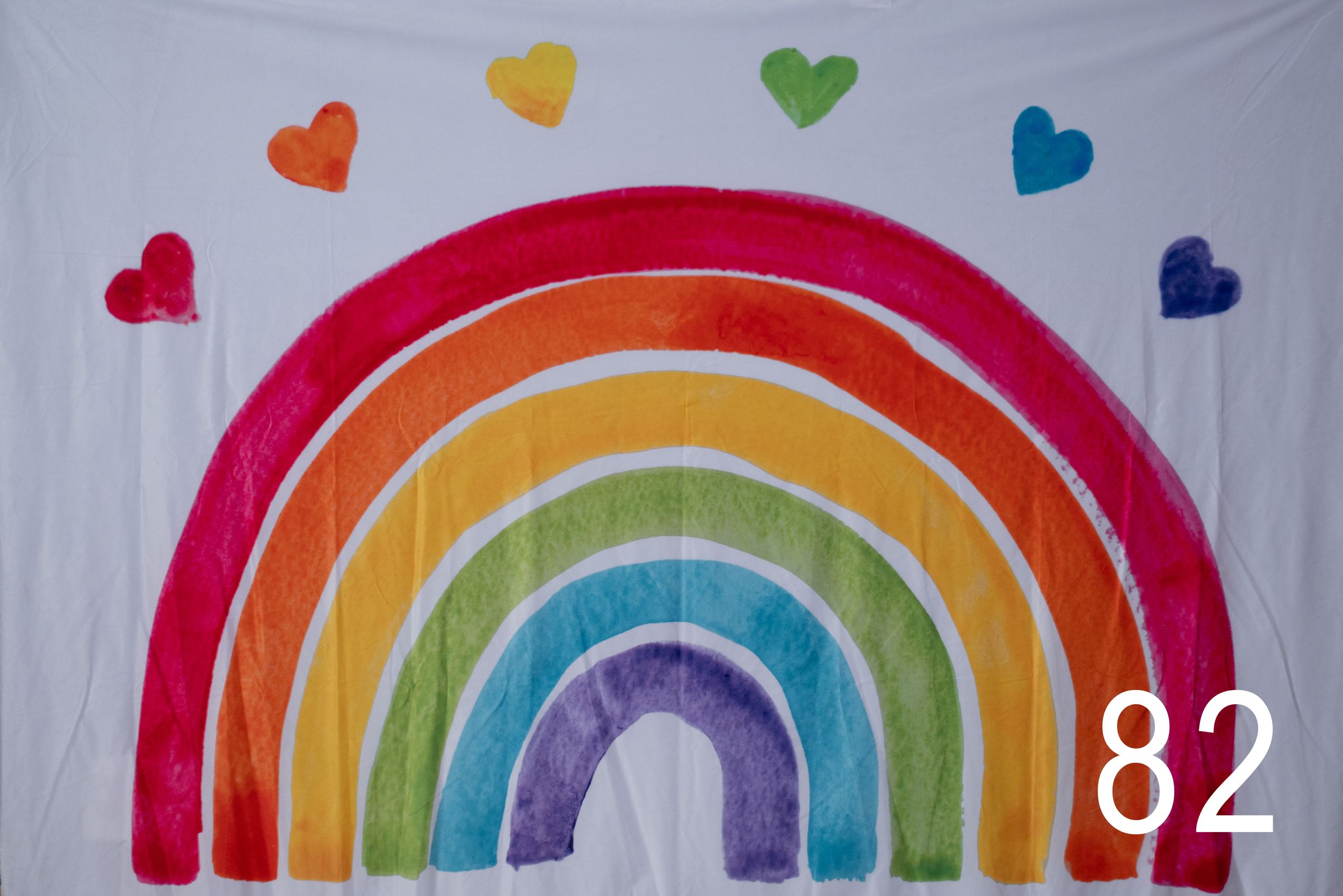 Colorful rainbow arches decorated with small hearts on a white fabric background.