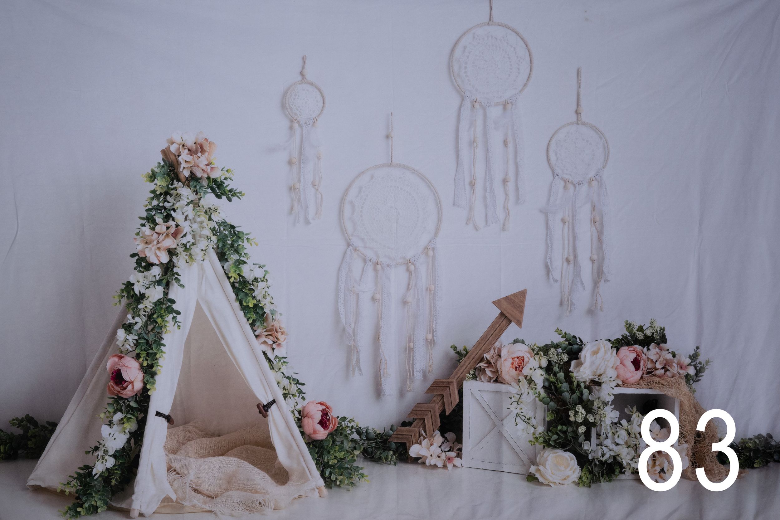 Bohemian dreamcatcher backdrop adorned with delicate floral arrangements and greenery creates a romantic wedding setting.