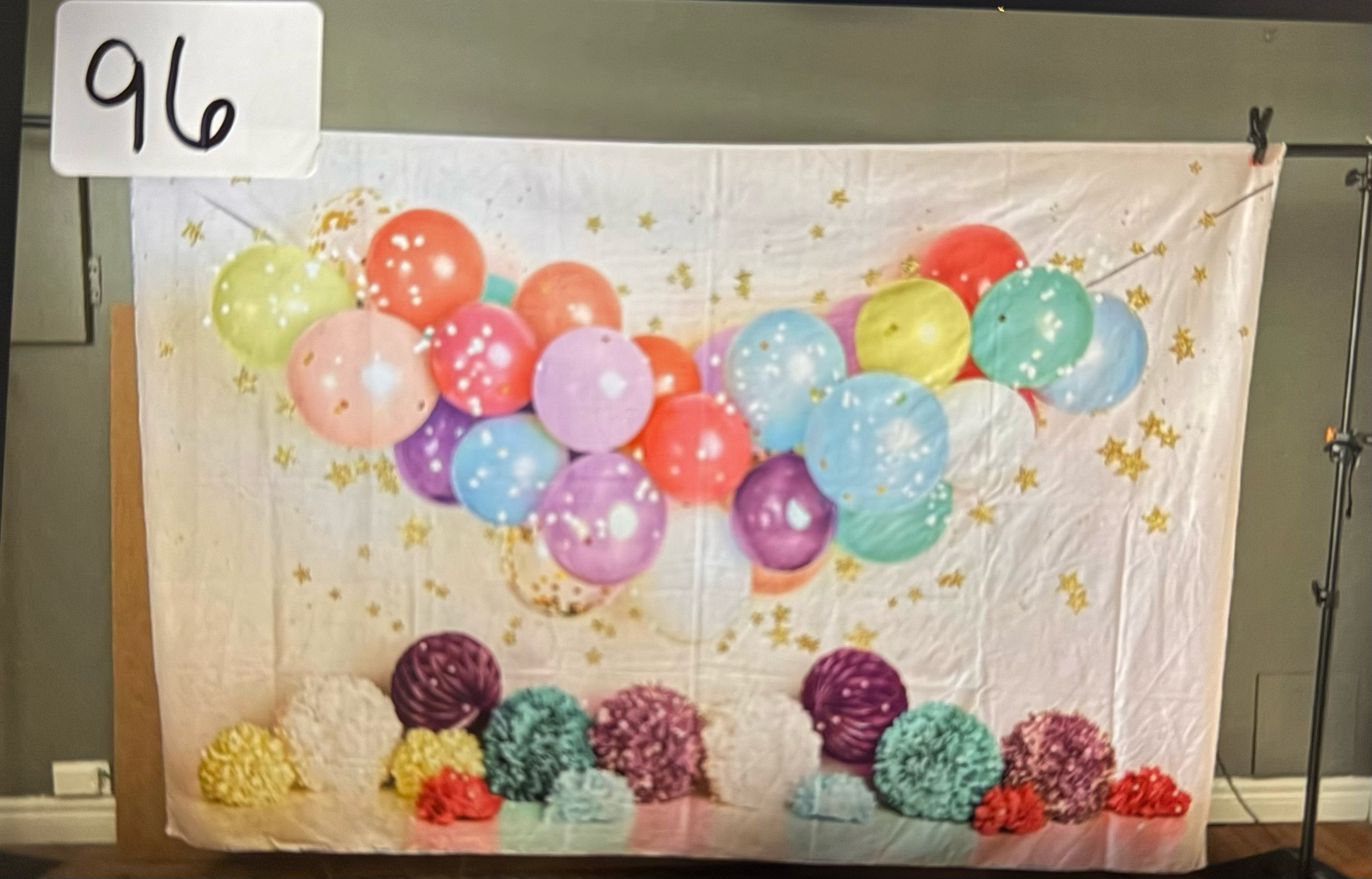 Colorful balloon garland artwork displayed on a white wall with vibrant watercolor-style splashes and confetti details.