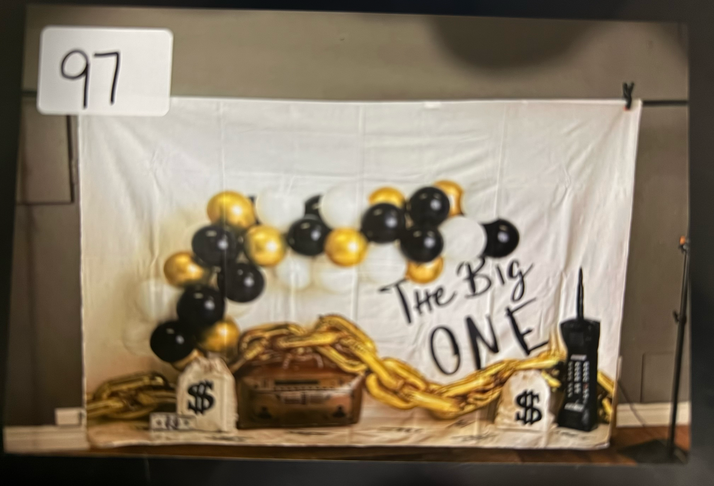 Black and gold balloon decorations with a white backdrop create an elegant party setup for a celebration.