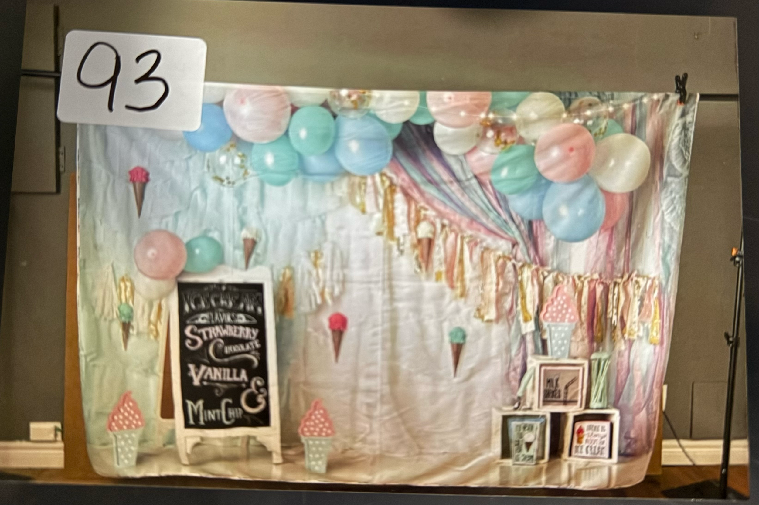 A festive party setup with pastel balloons and decorative elements against a white backdrop for a celebration.