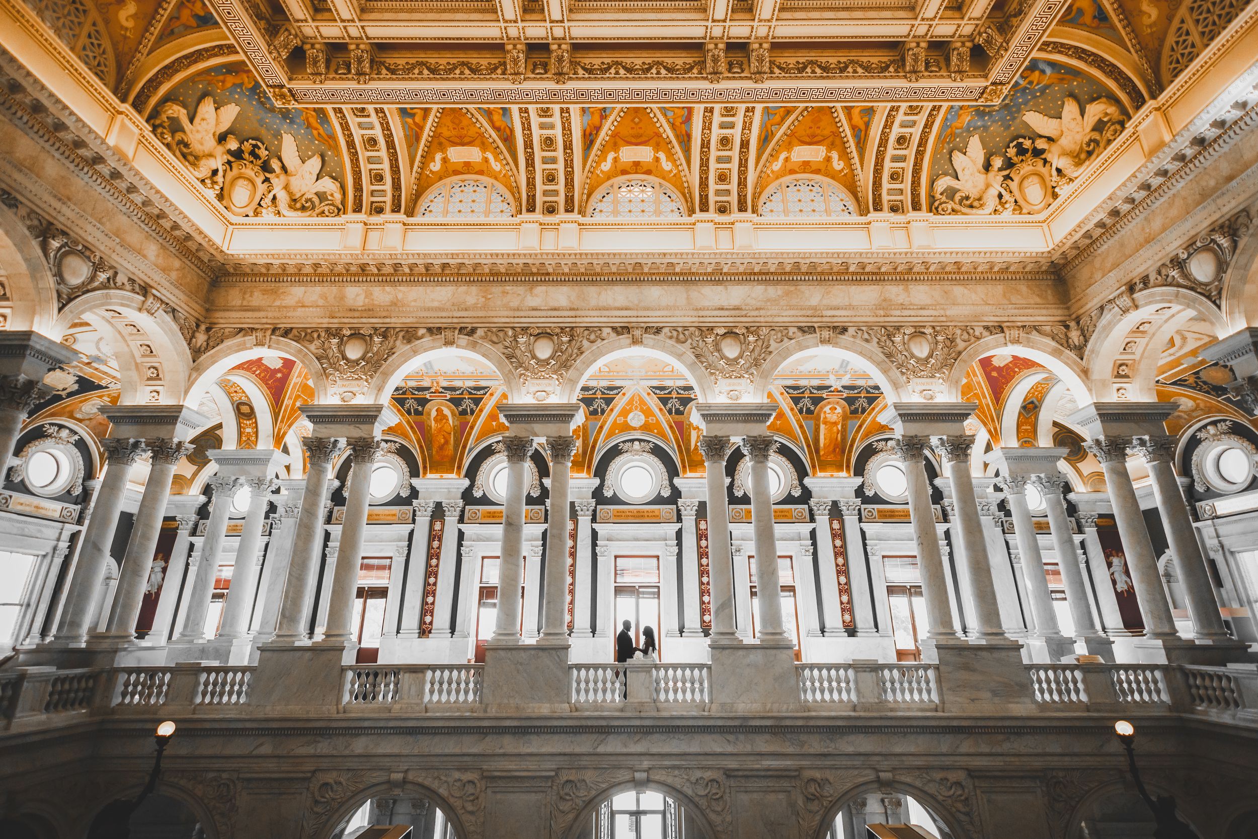 Ornate baroque architecture with gilded details adorns the ceiling and walls of a grand historic palace interior of the Library of Congress