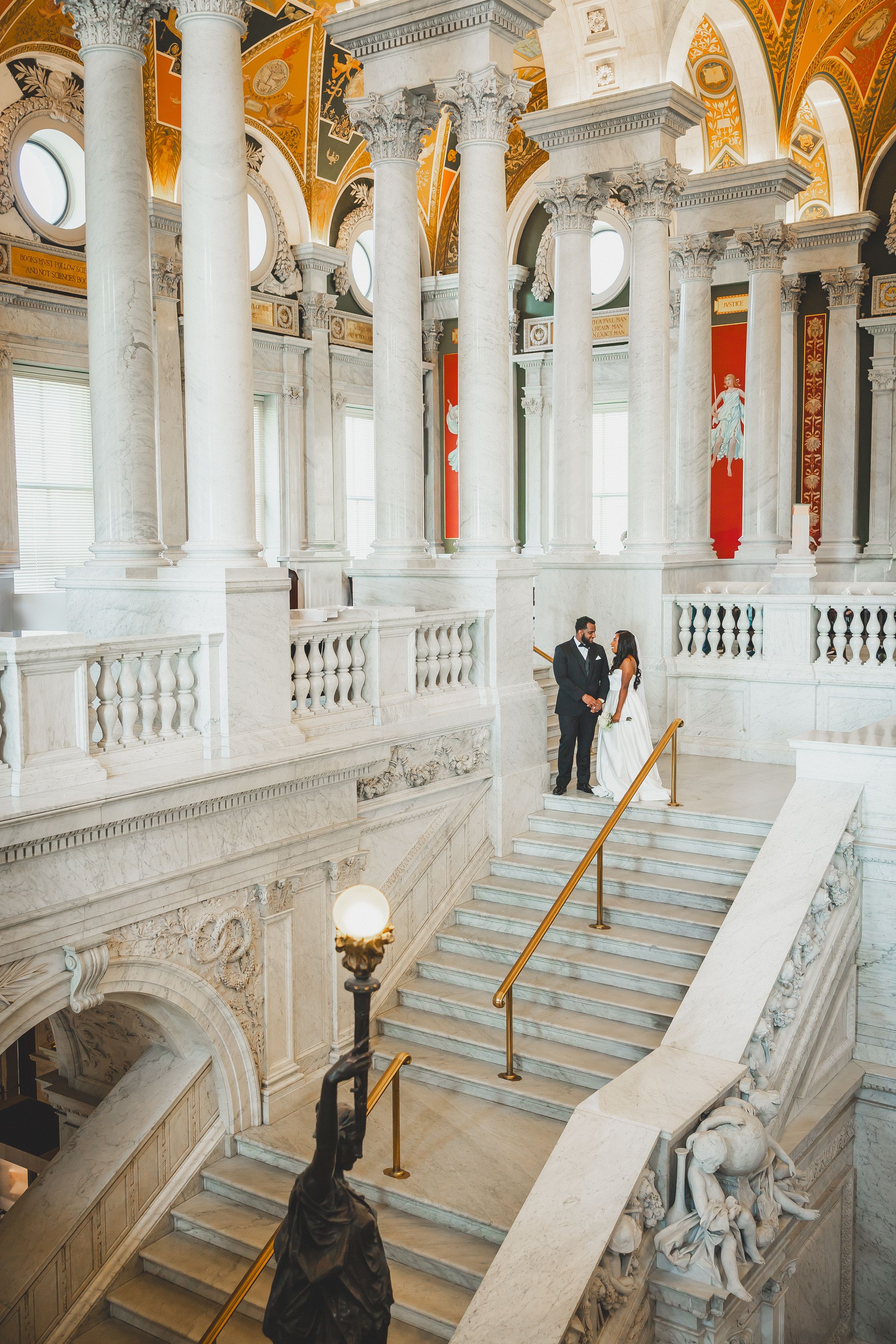 Elegant marble staircase with ornate columns and gilded ceiling inside the Library of Congress in Washington DC.