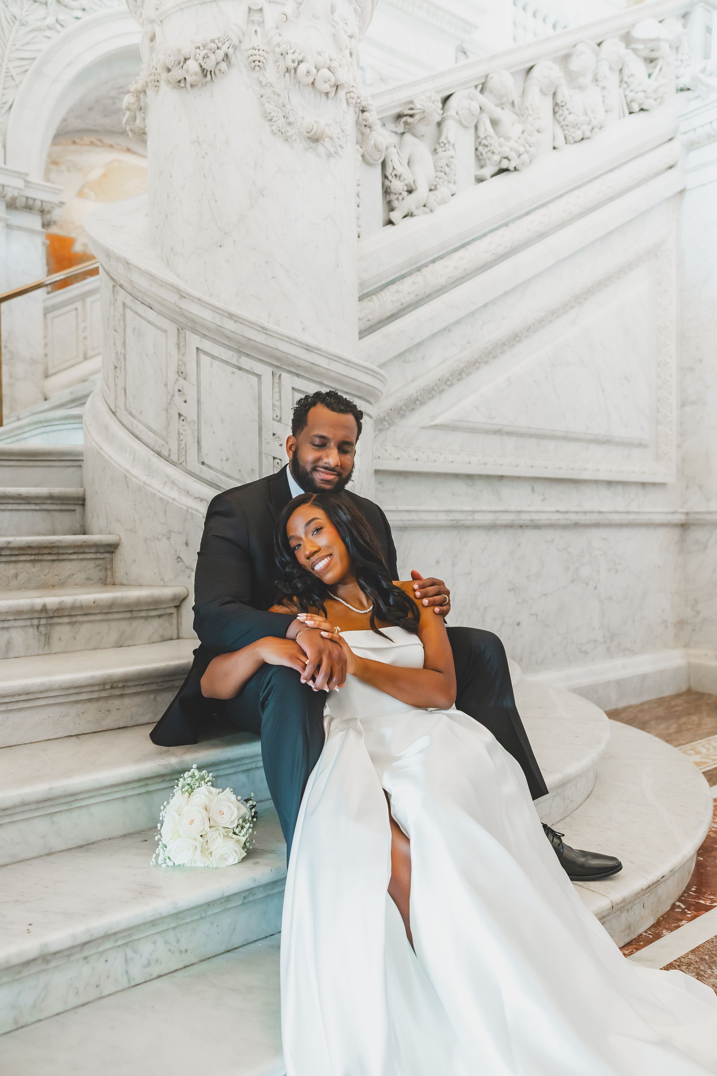 A joyful couple shares laughter while sitting together on elegant white marble stairs at Library of Congress