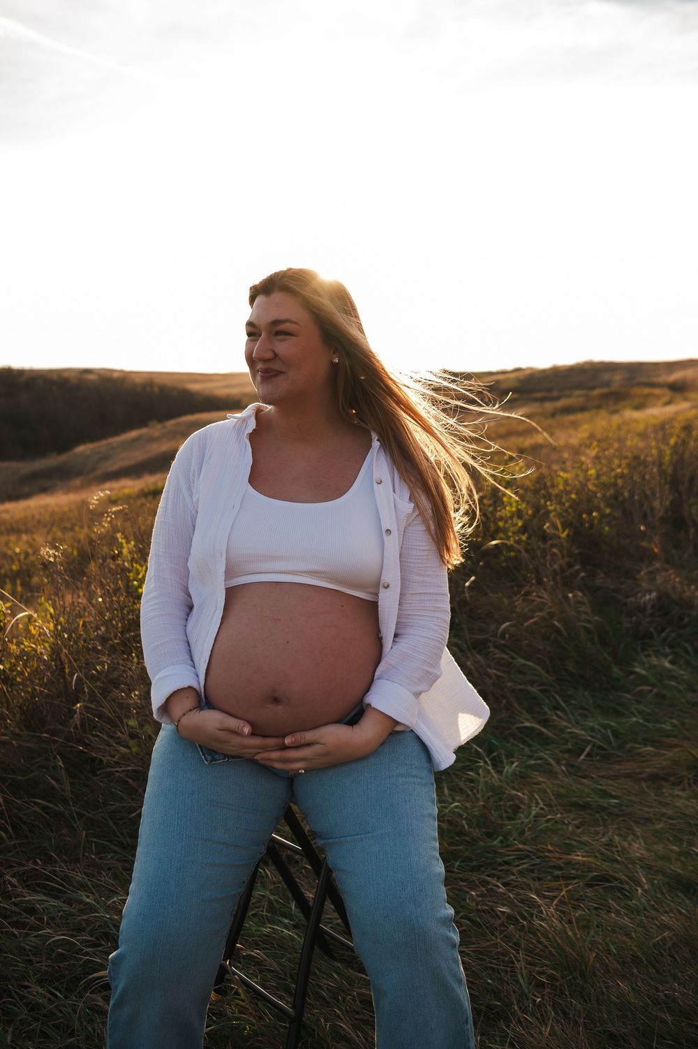 Maternity photos in rustic field setting during golden hour.