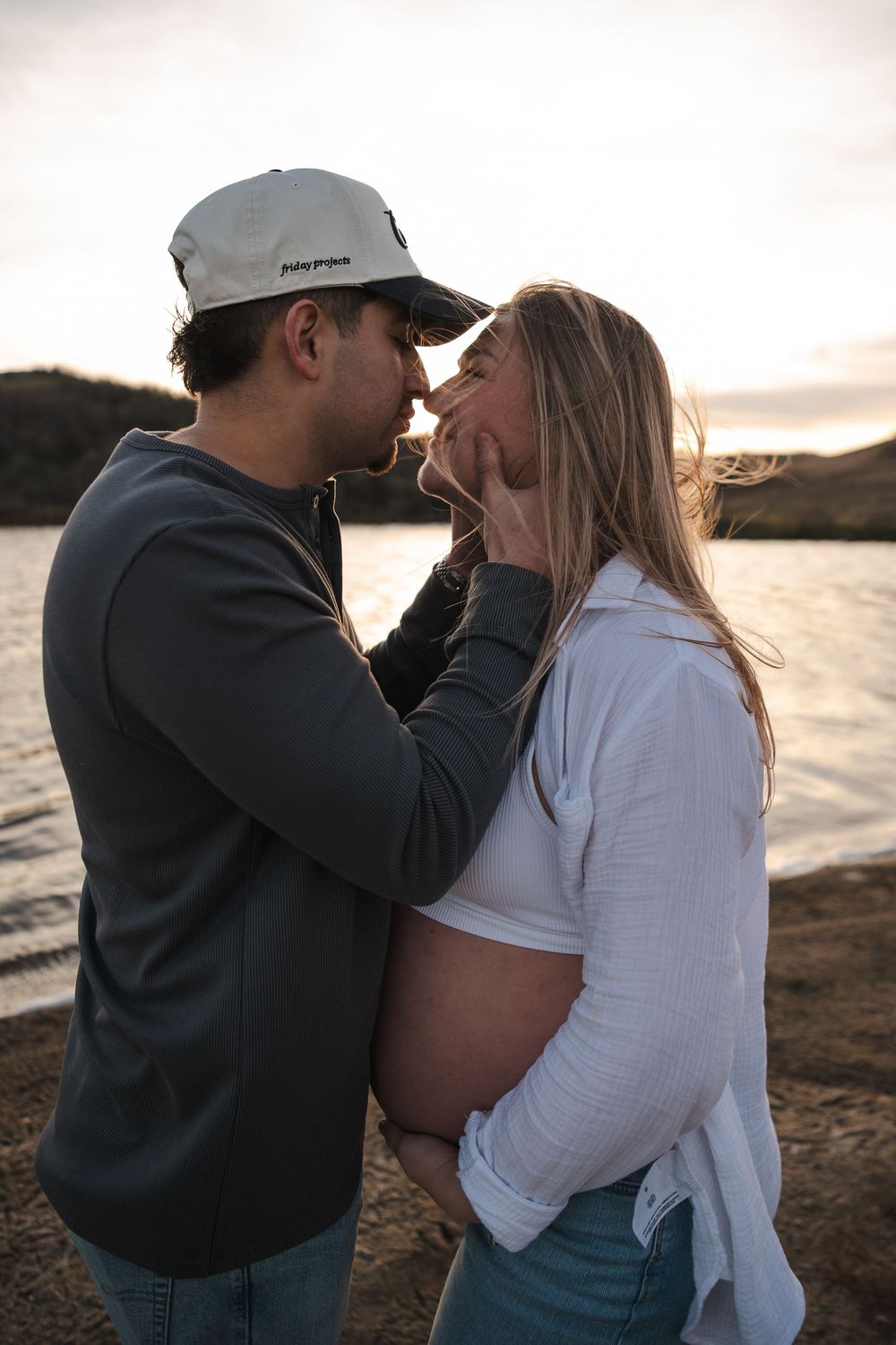 Intimate couple's moment captured at waterfront during sunset.