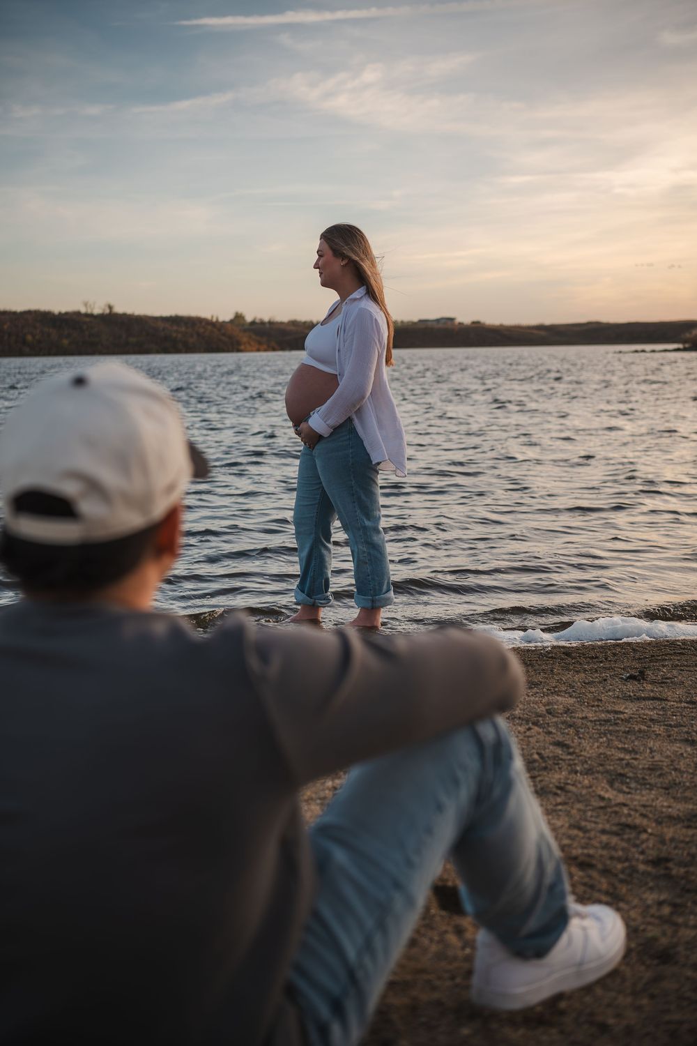 Couple enjoying peaceful moment by lake at sunset with scenic water view.