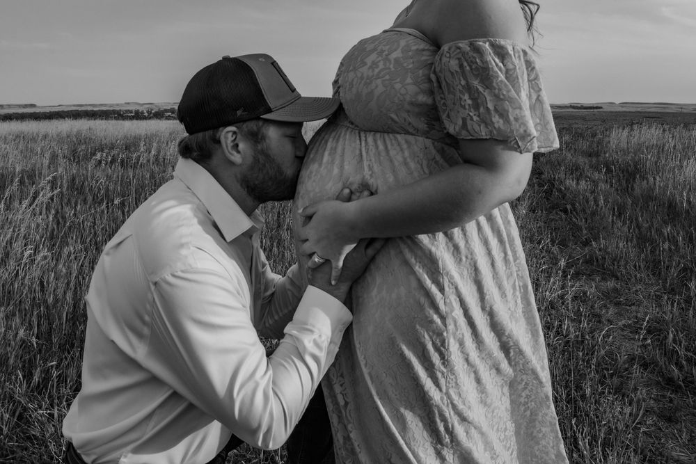Black and white maternity photo showing tender moments in a field.
