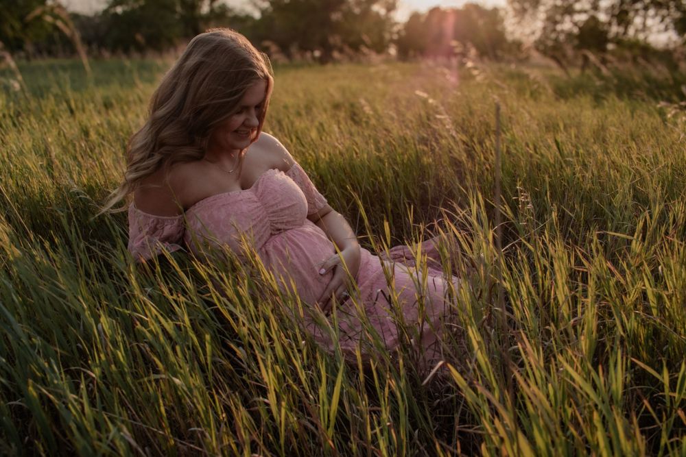 Romantic maternity photoshoot in a golden field at sunset.