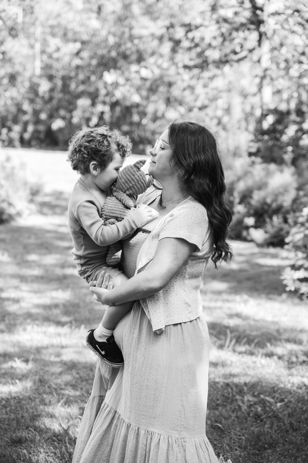 A tender black and white photo series showing a parent and small child embracing outdoors in a garden setting.