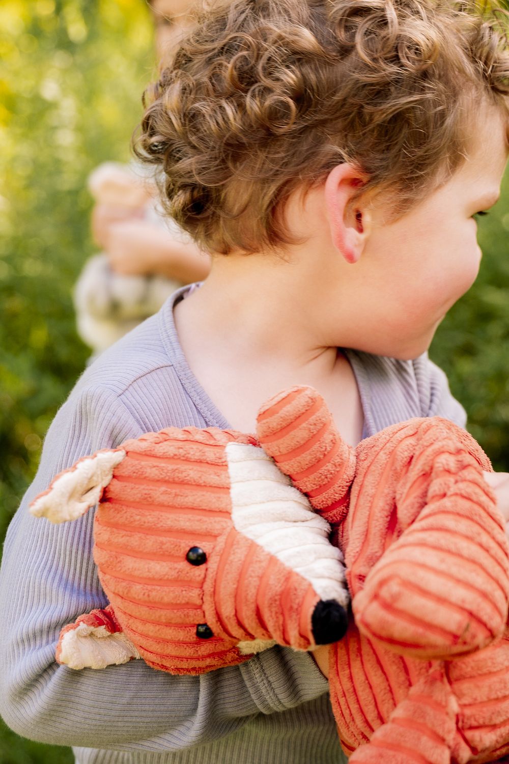 A person in a gray sweater hugging a large plush orange lobster toy in a series of four photos.