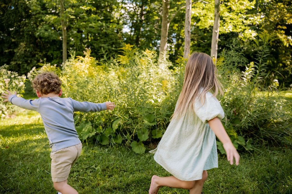 A couple embraces while dancing in a sunlit garden with lush green foliage surrounding them.