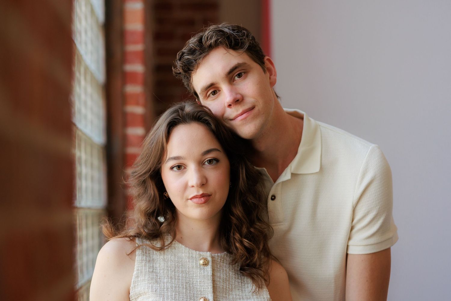 Two people in light colored outfits pose together against a white backdrop during a studio photoshoot session.