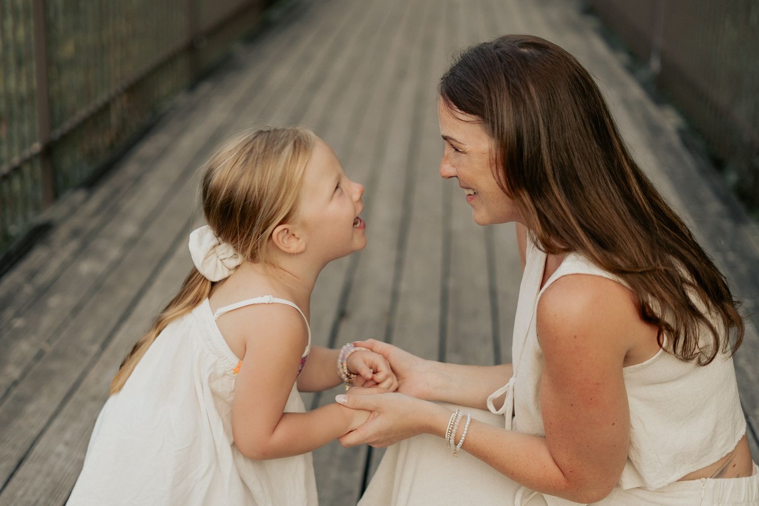 A series of candid moments between parent and child laughing together on wooden boardwalk in summer.