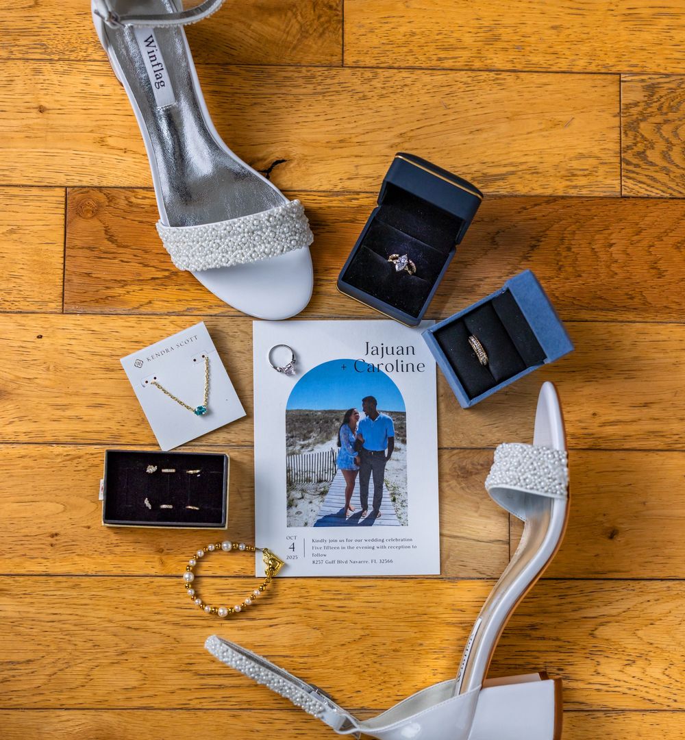 Wedding accessories and jewelry arranged on a wooden floor with photos and decorative items.