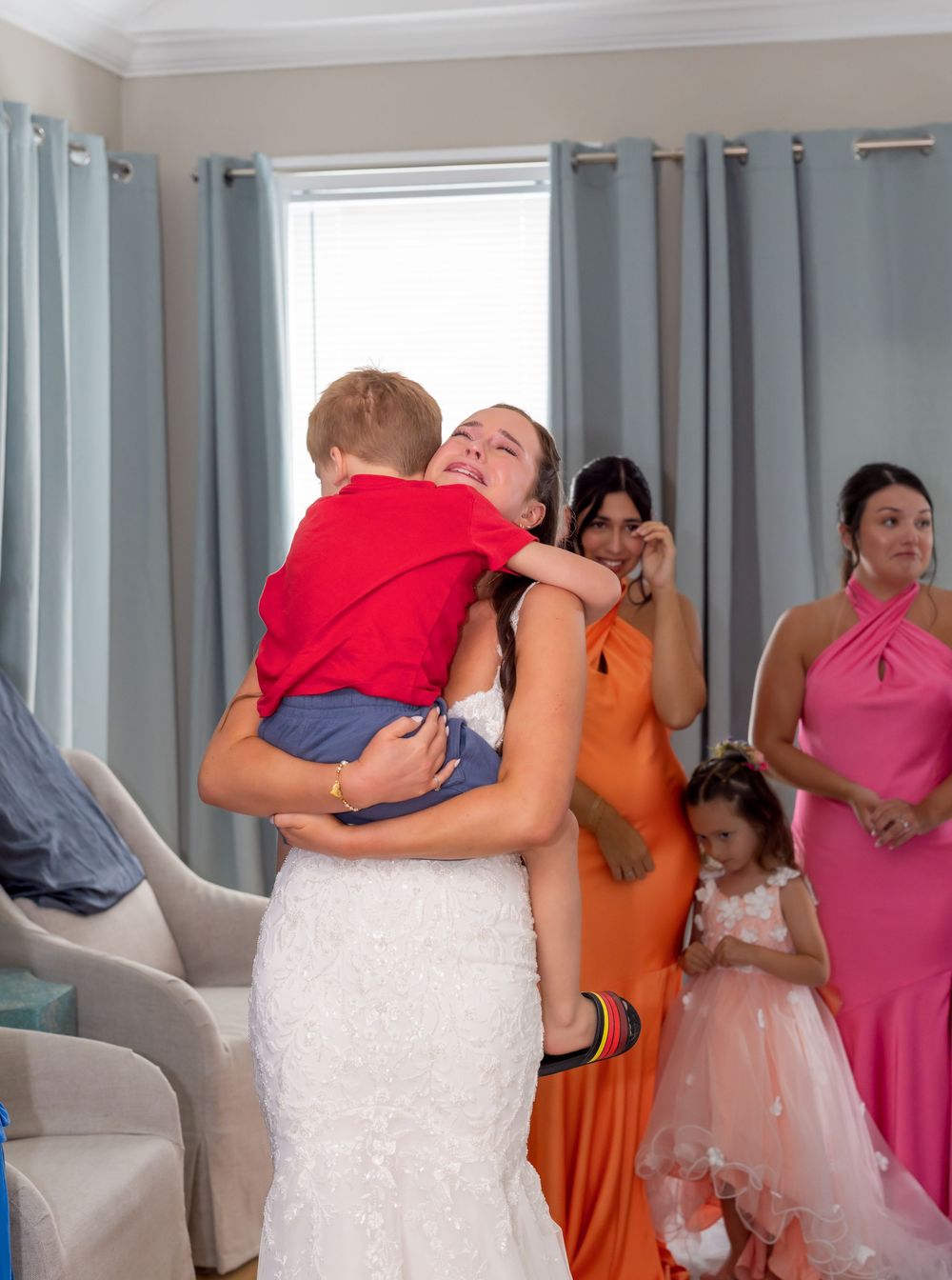 A sequence of wedding party photos showing emotional embraces and hugs in a room with blue curtains.