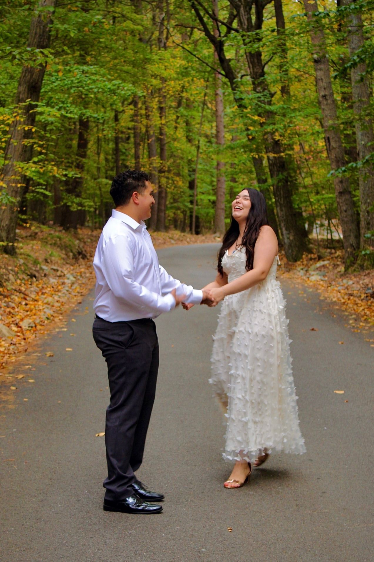 A couple dancing together on a fall day in a wooded area.