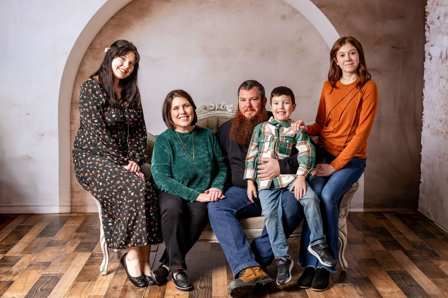 Studio portrait of a family group seated together under an arched doorway.